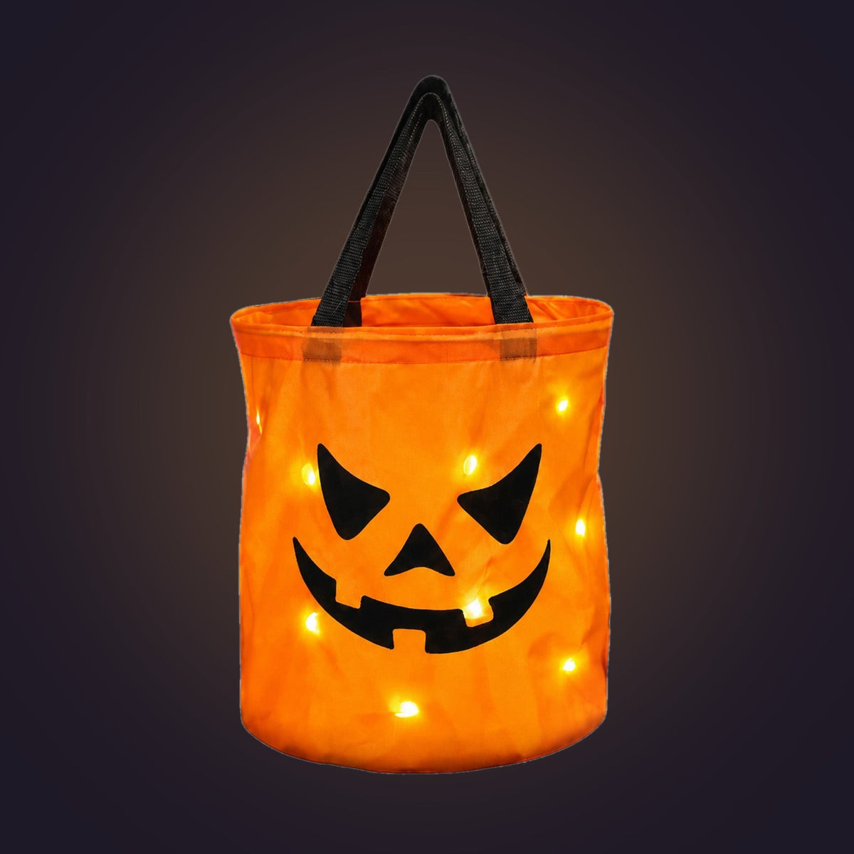 Orange light-up pumpkin candy bucket with black handles, glowing, on a dark background